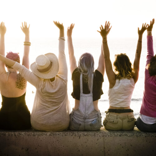 rear view of group of females caucasian friends enjoying at the sunset with ocean in background - success and satisfaction concept for nice people together with joy - friendship and vacation